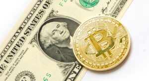 A Bitcoin placed on top of a US dollar bill, symbolizing the intersection of cryptocurrency and traditional finance.