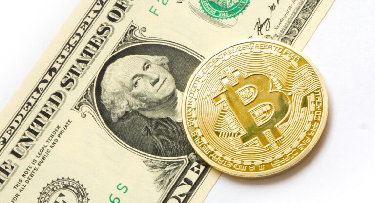 A Bitcoin placed on top of a US dollar bill, symbolizing the intersection of cryptocurrency and traditional finance.