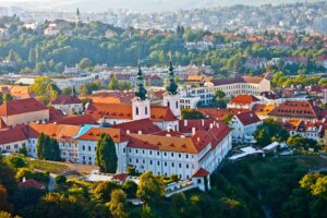 A scenic view of Prague, Czech Republic, showcasing historic architecture and the Vltava River at sunset.