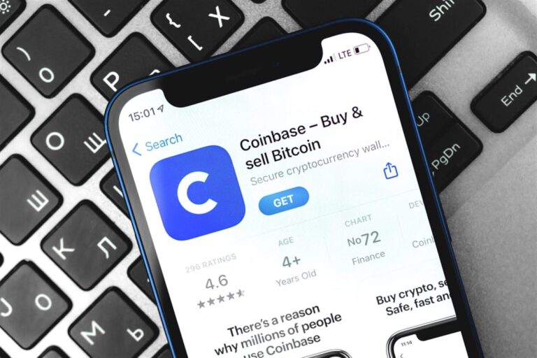 A smartphone displaying the Coinbase logo, placed on a financial chart with stock market data in the background, representing cryptocurrency trading and market trends.