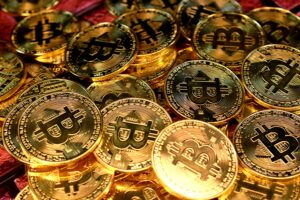 A close-up of gold and silver Bitcoin coins stacked on a reflective surface, symbolising cryptocurrency and digital assets.